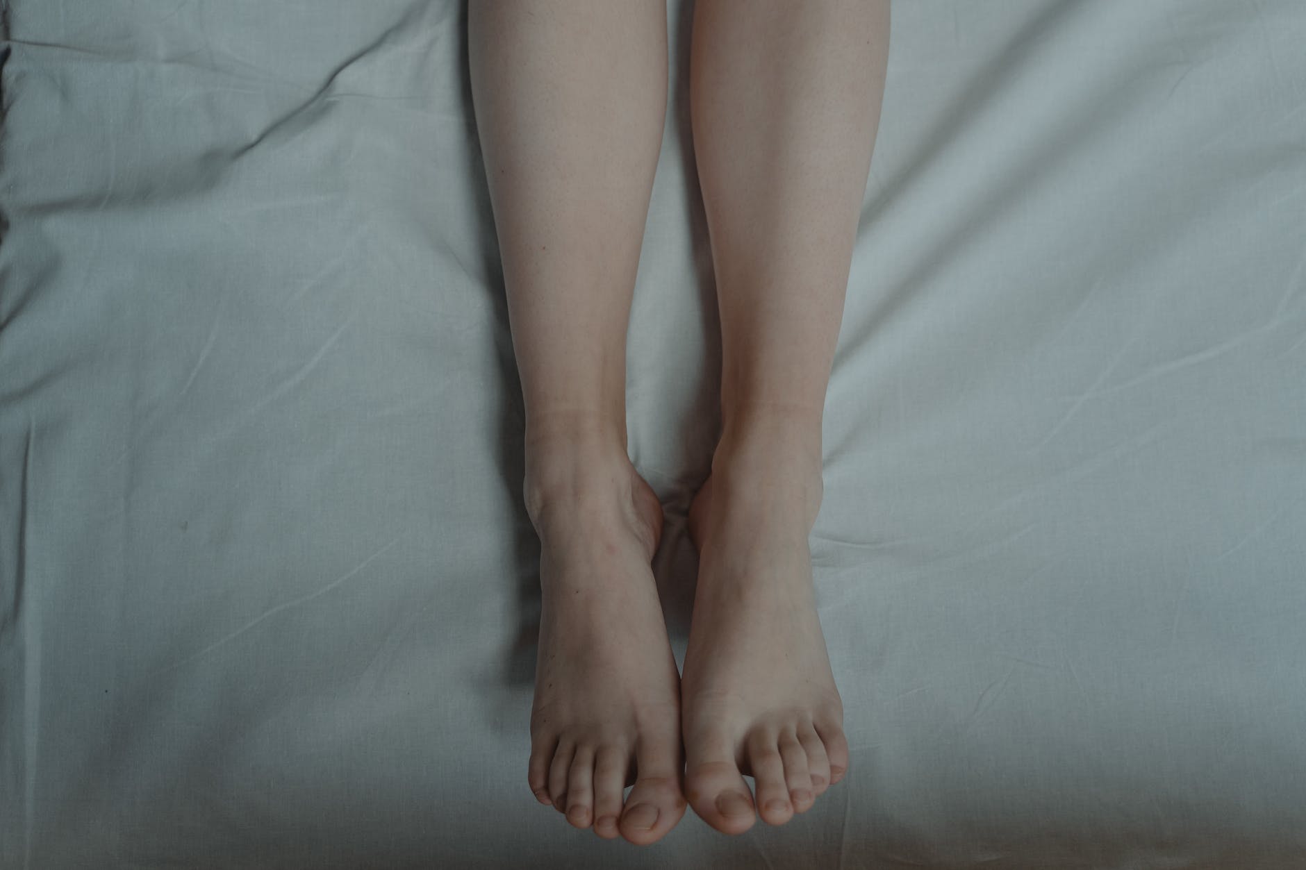 barefoot person lying in bed