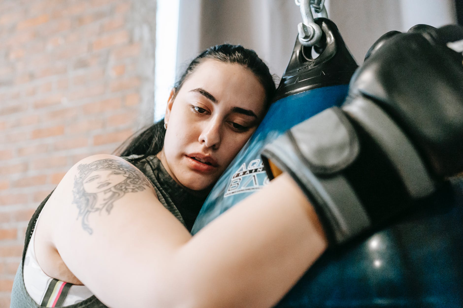weary woman embracing punching bag after hard training