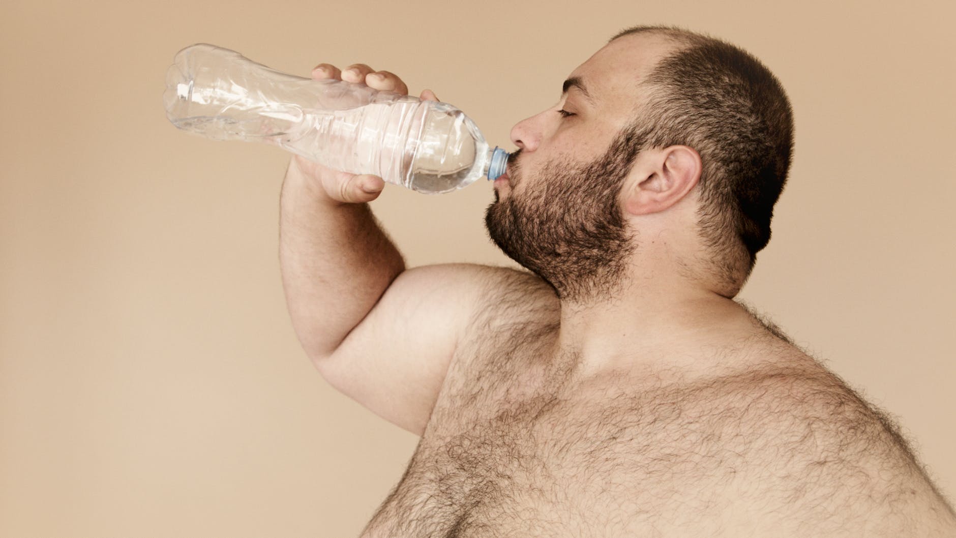 man drinking from clear plastic bottle
