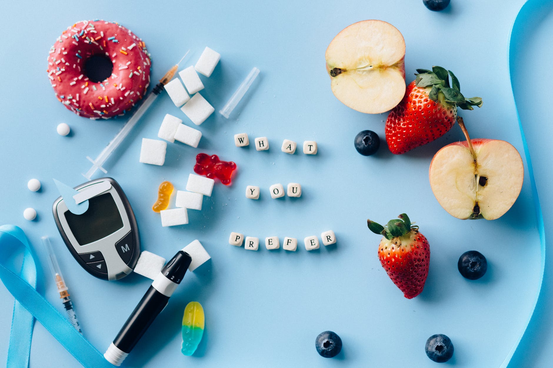 letter dices between fresh fruits and diabetes equipment on a blue surface