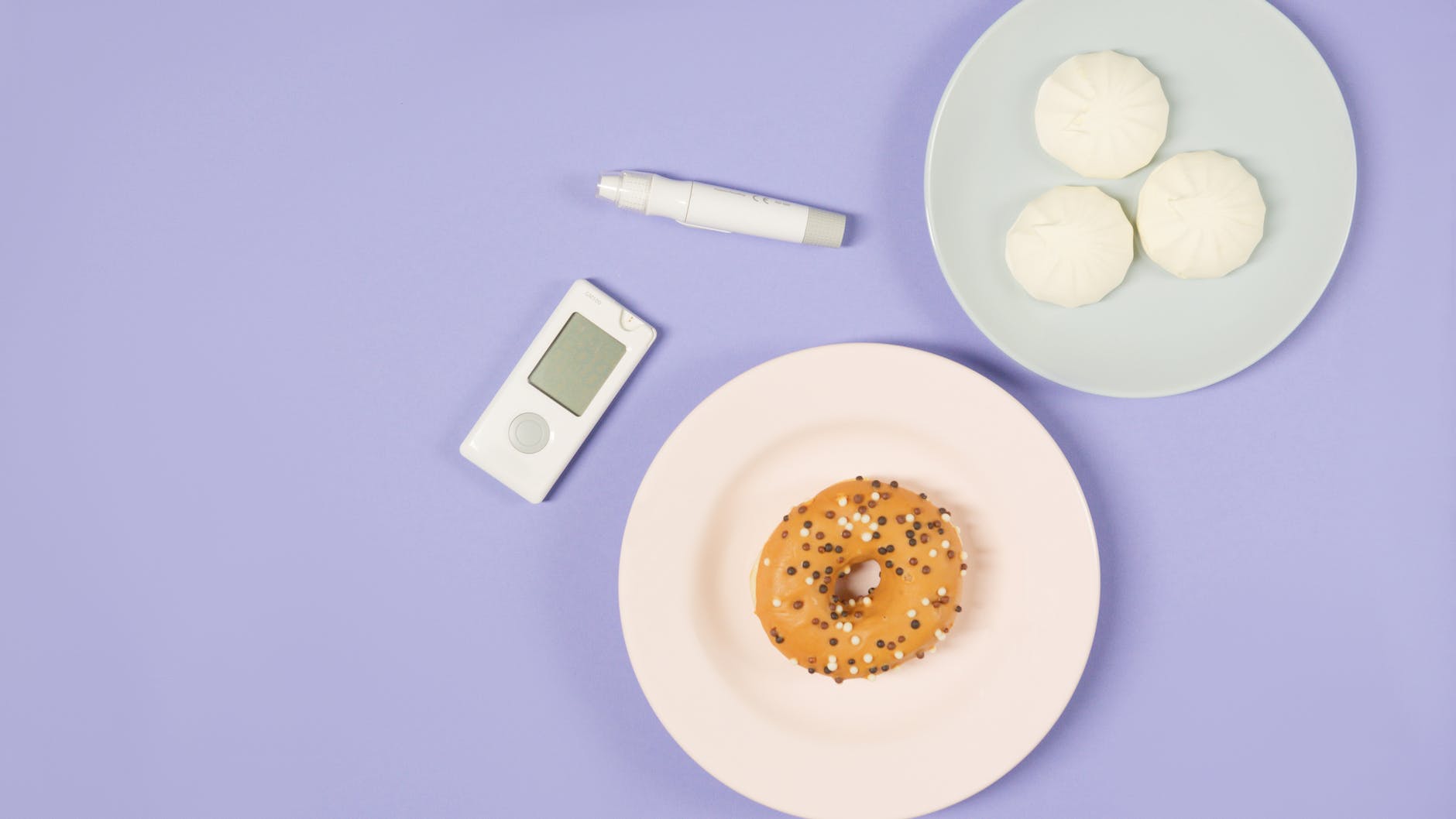 glucometer and insulin pen beside plates of donut and steamed buns