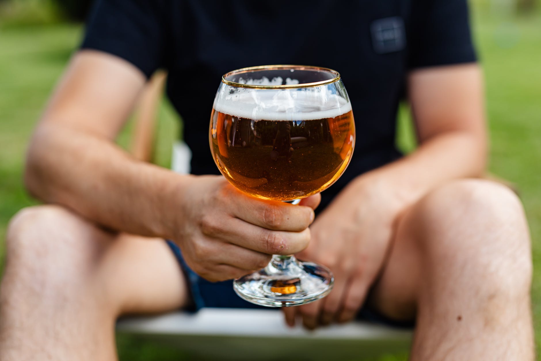 man holding clear glass with beer