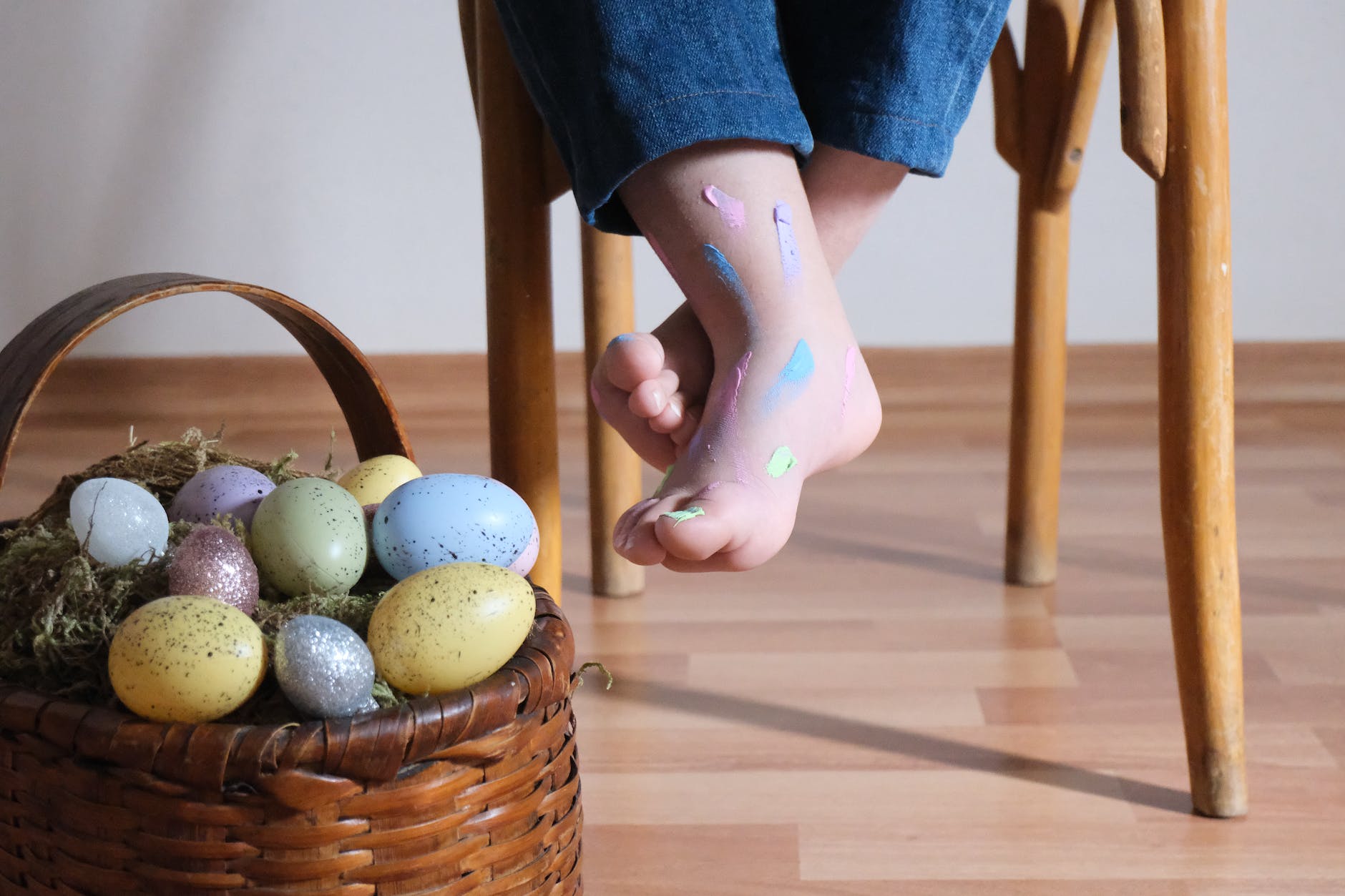 basket of easter eggs and bare feet of a boy sitting on a chair