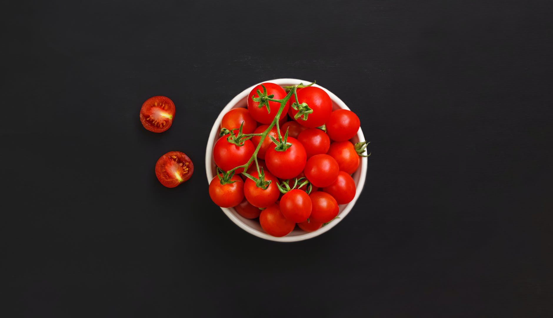 bowl with ripe cherry tomatoes on black background