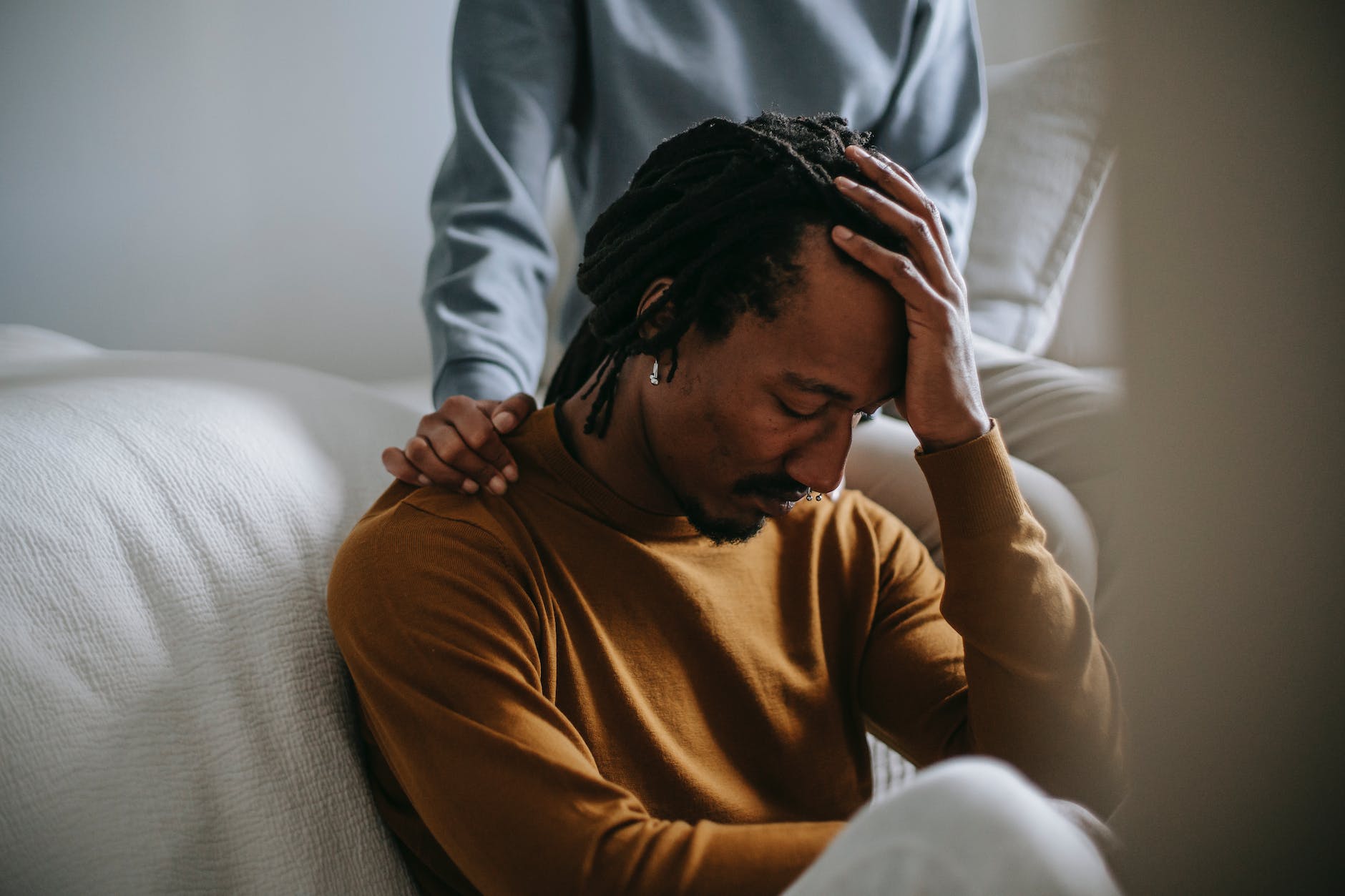 sorrowful black man touching head in dismay near supporting wife