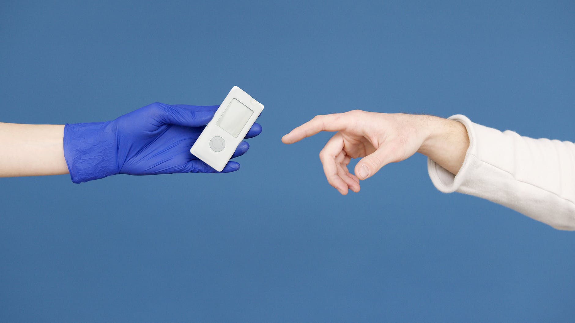 person s hand in latex gloves holding a glucometer