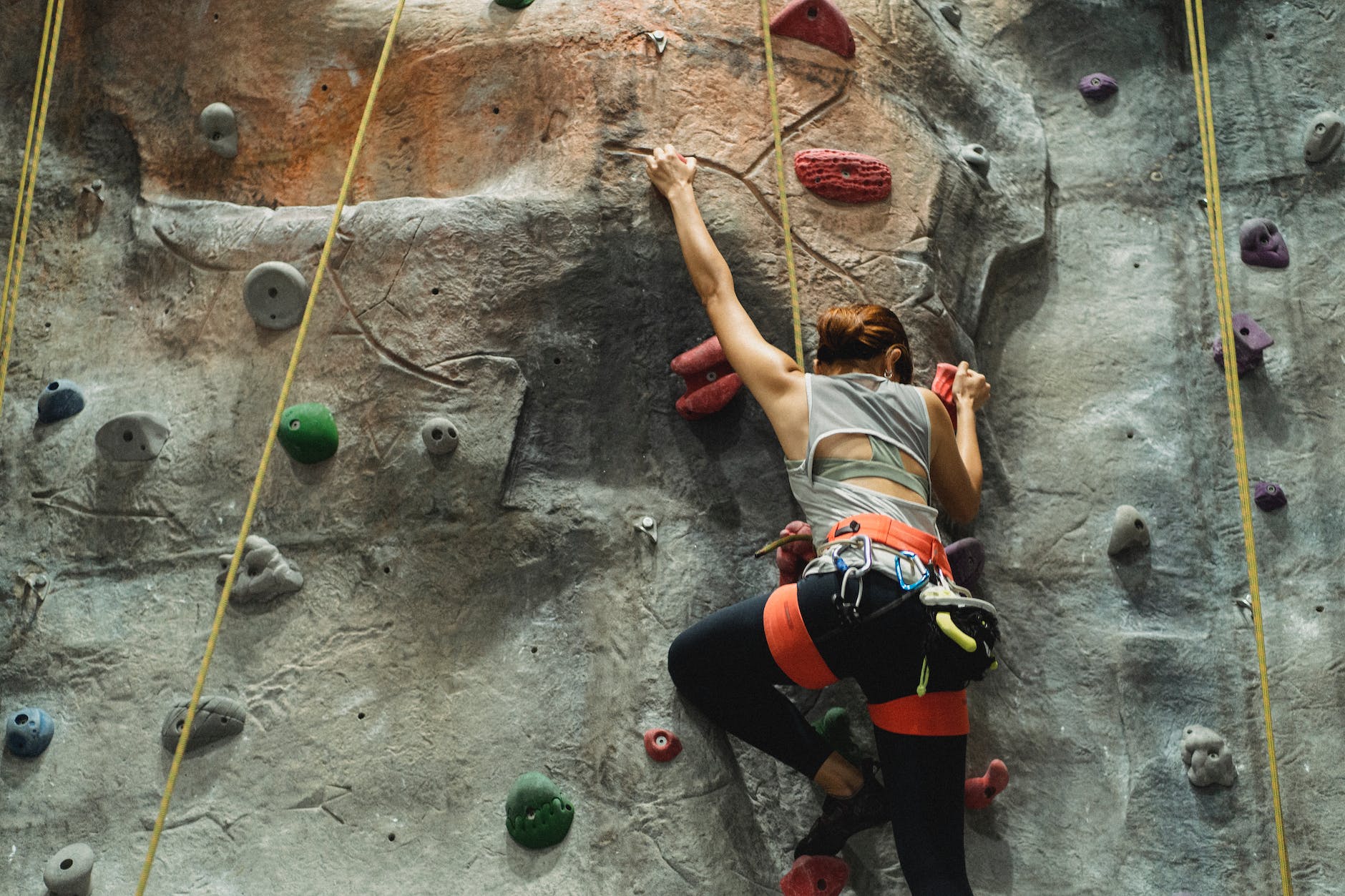 unrecognizable climber ascending artificial rock during practice