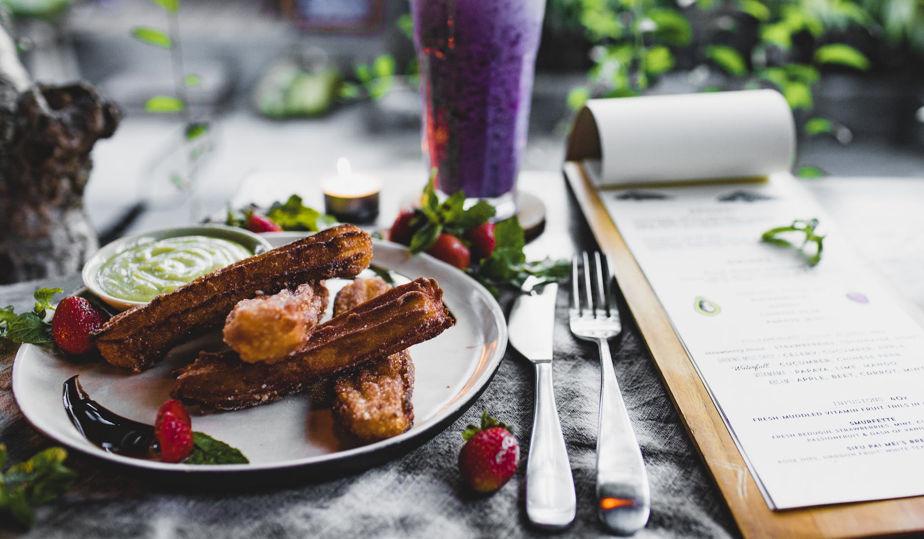 plate of delicious churros with sauce served on table with smoothie