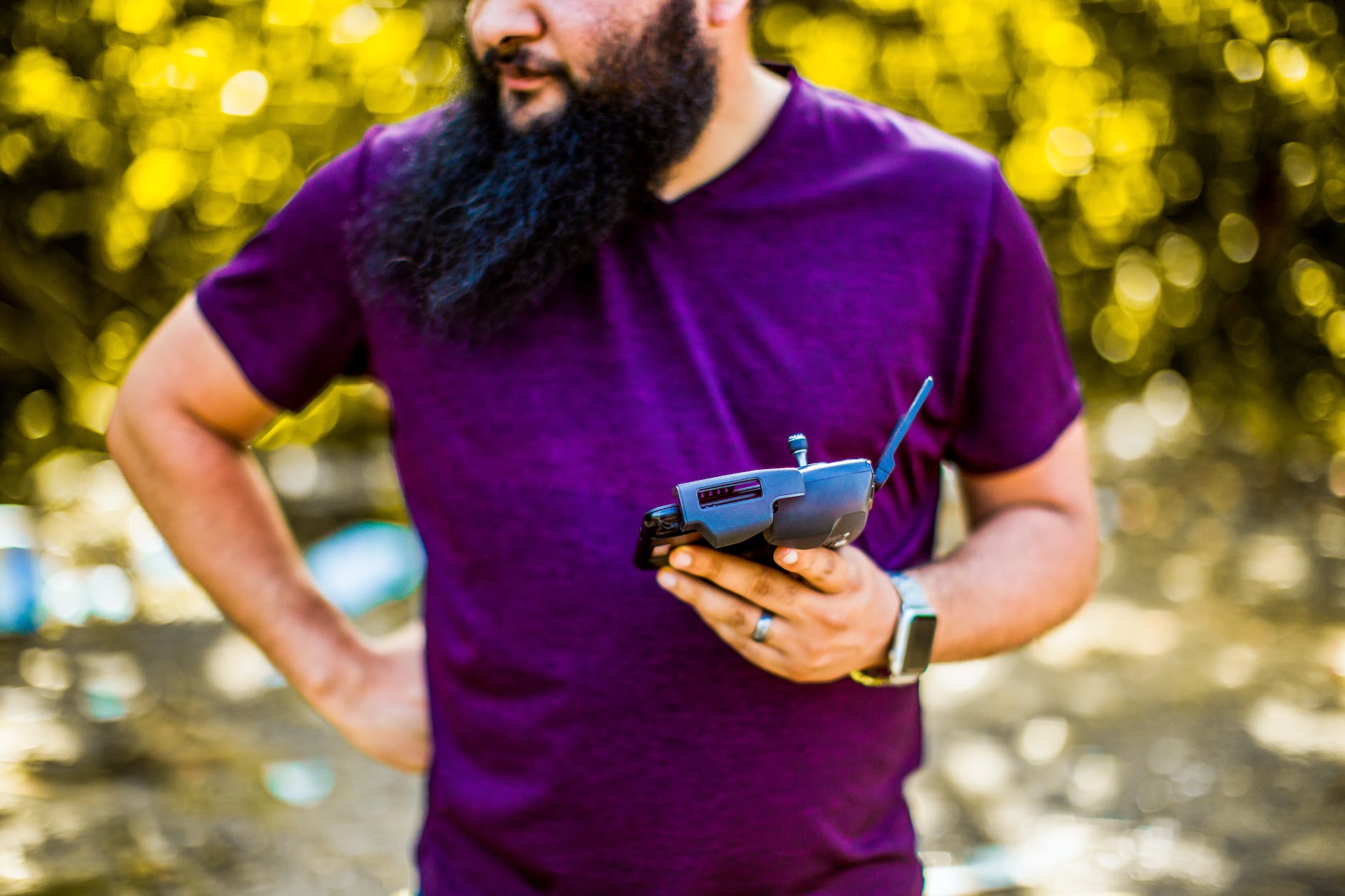 man standing with smartphone with controller for drone in hand in daytime